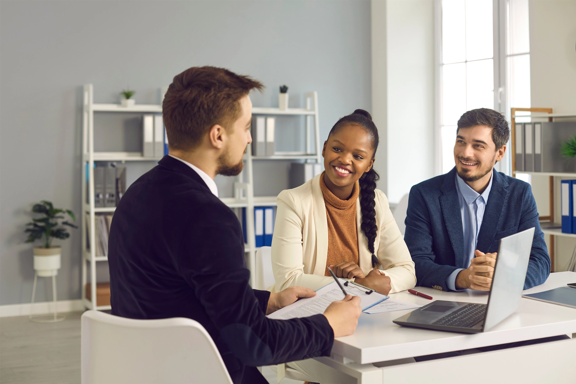 Group of people sitting around a laptop talking in a meeting