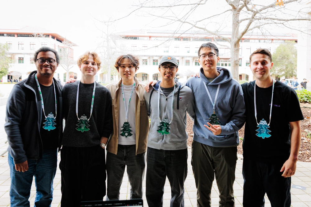 Six hackers pose together outdoors wearing TreeHacks lanyards