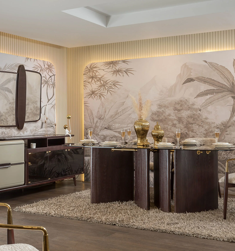 Modern dining room with dark wood table featuring gold vases and glassware, beige patterned wallpaper with botanical motifs, and matching sideboard.
