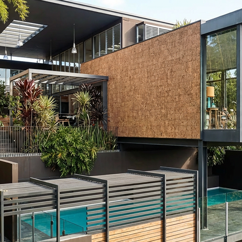 Modern rectangular house elevated on stilts surrounded by trees and natural landscape under a clear blue sky.