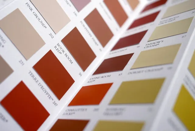 Close-up of a color palette book showing various shades of red, brown, cream, and yellow with labels and codes.