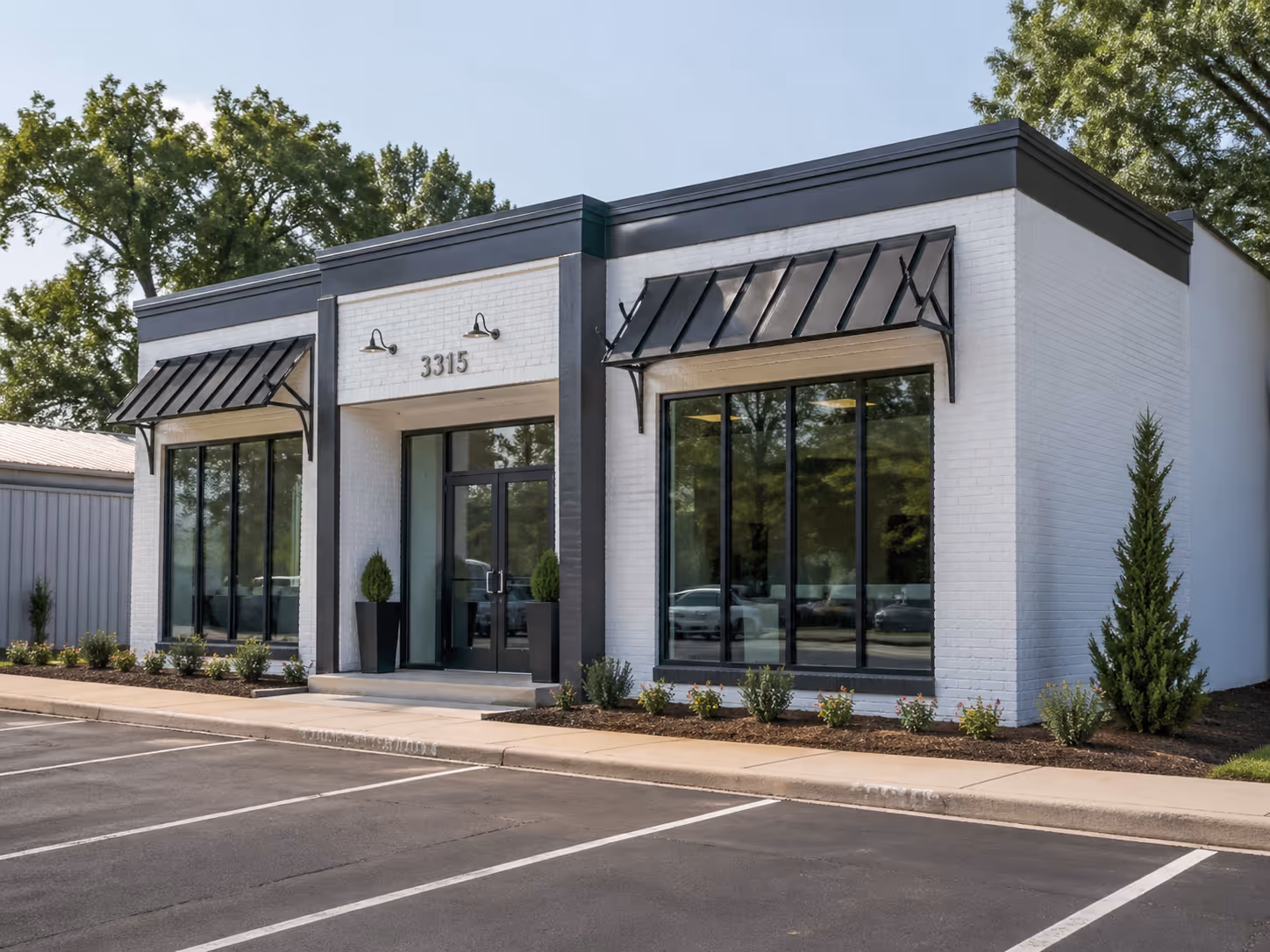 Modern white brick commercial building with large black-framed windows, black awnings, and the number 3315 above the entrance.