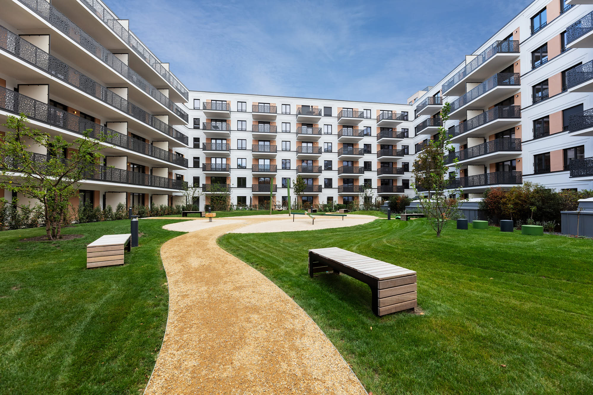 Moderner Innenhof einer Berliner Wohnanlage mit Balkonen, Grünflächen und Sitzbereichen