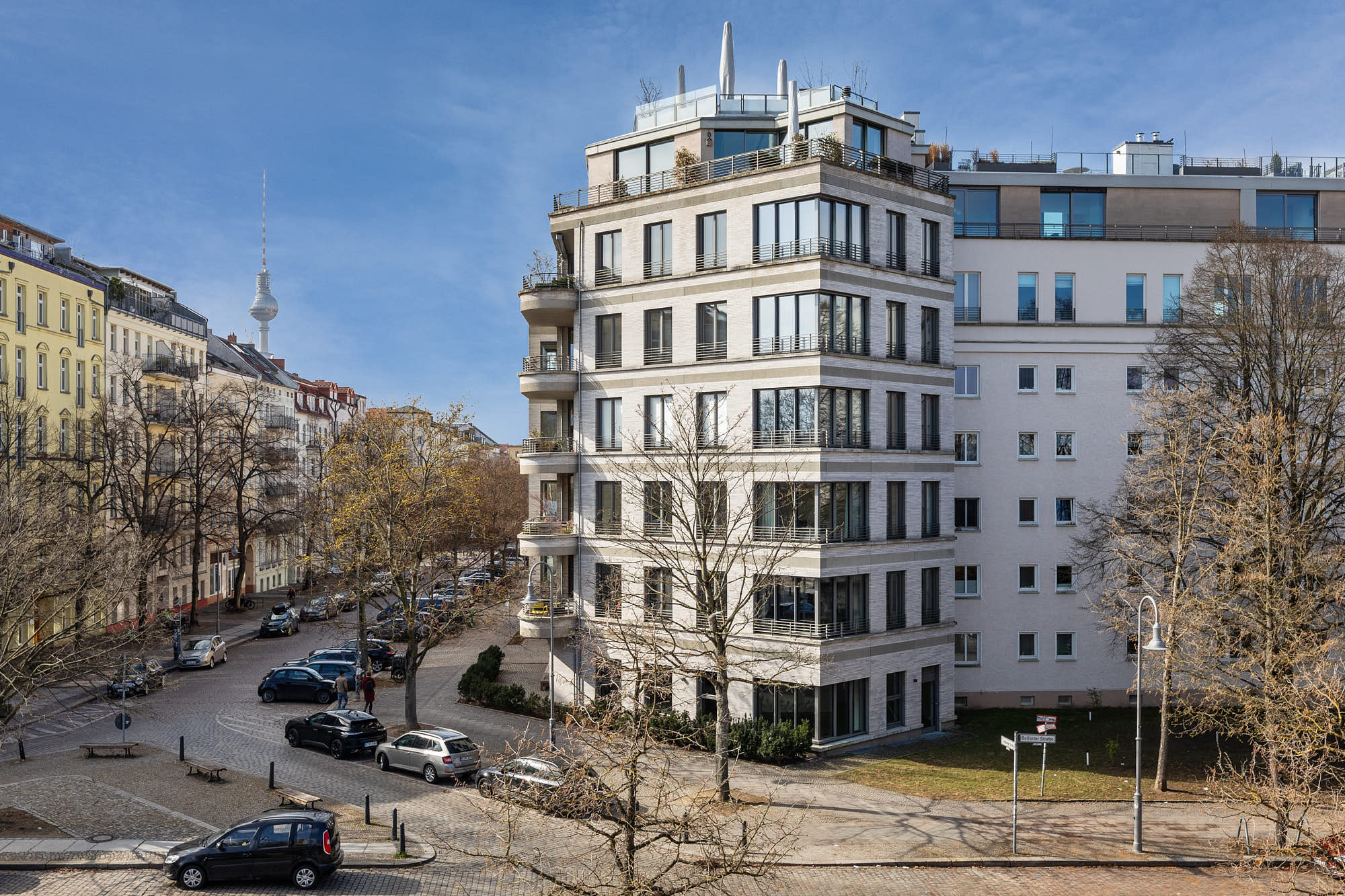 Modernes Wohngebäude in Berlin mit Balkonen, Straßenraum und Fernsehturm im Hintergrund
