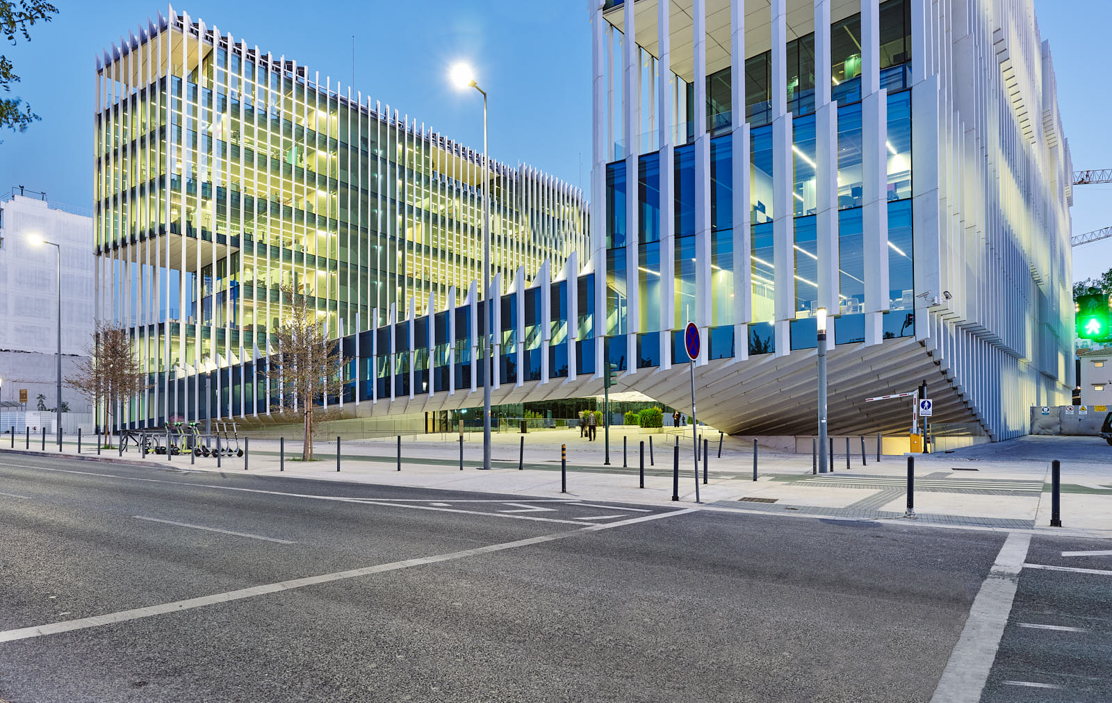 Modernes Bürogebäude in Lissabon mit vertikalen Fassadenelementen und beleuchteten Innenräumen in der Dämmerung