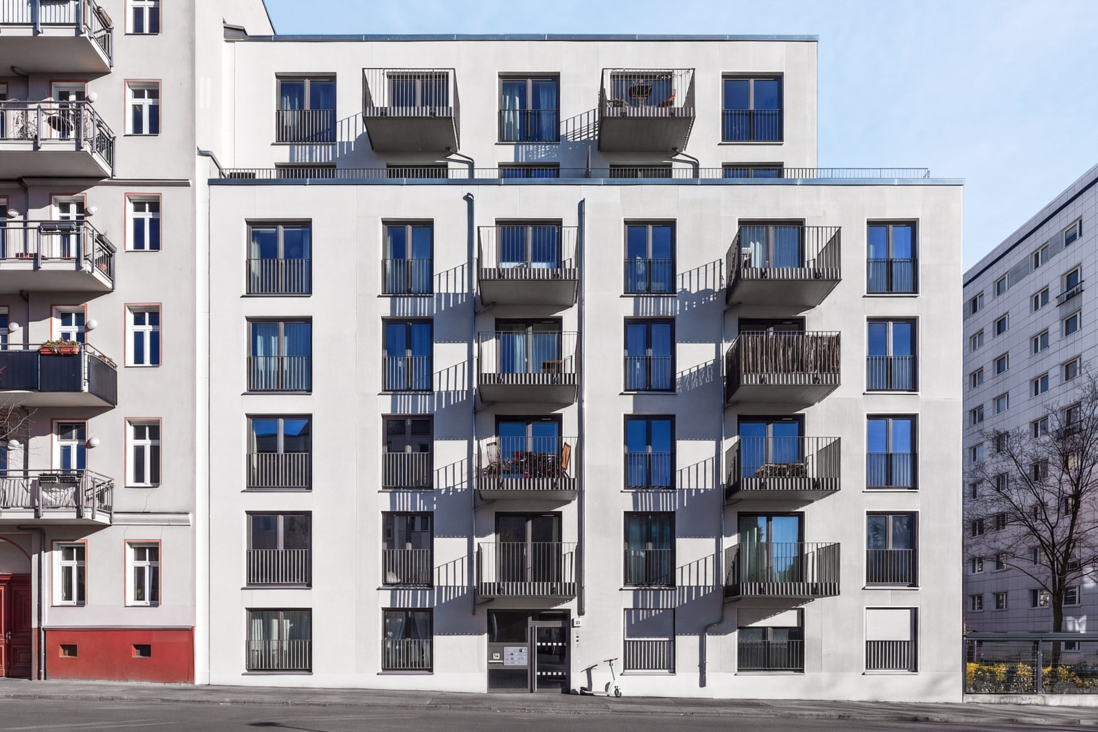 Modernes Mehrfamilienhaus in Berlin mit heller Fassade, französischen Balkonen und straßenseitiger Ansicht