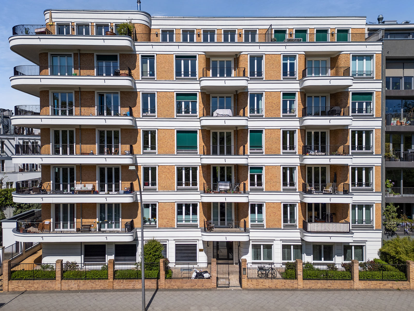 Modernes Mehrfamilienhaus in Berlin mit heller Ziegelfassade, großen Balkonen und symmetrischer Straßenansicht