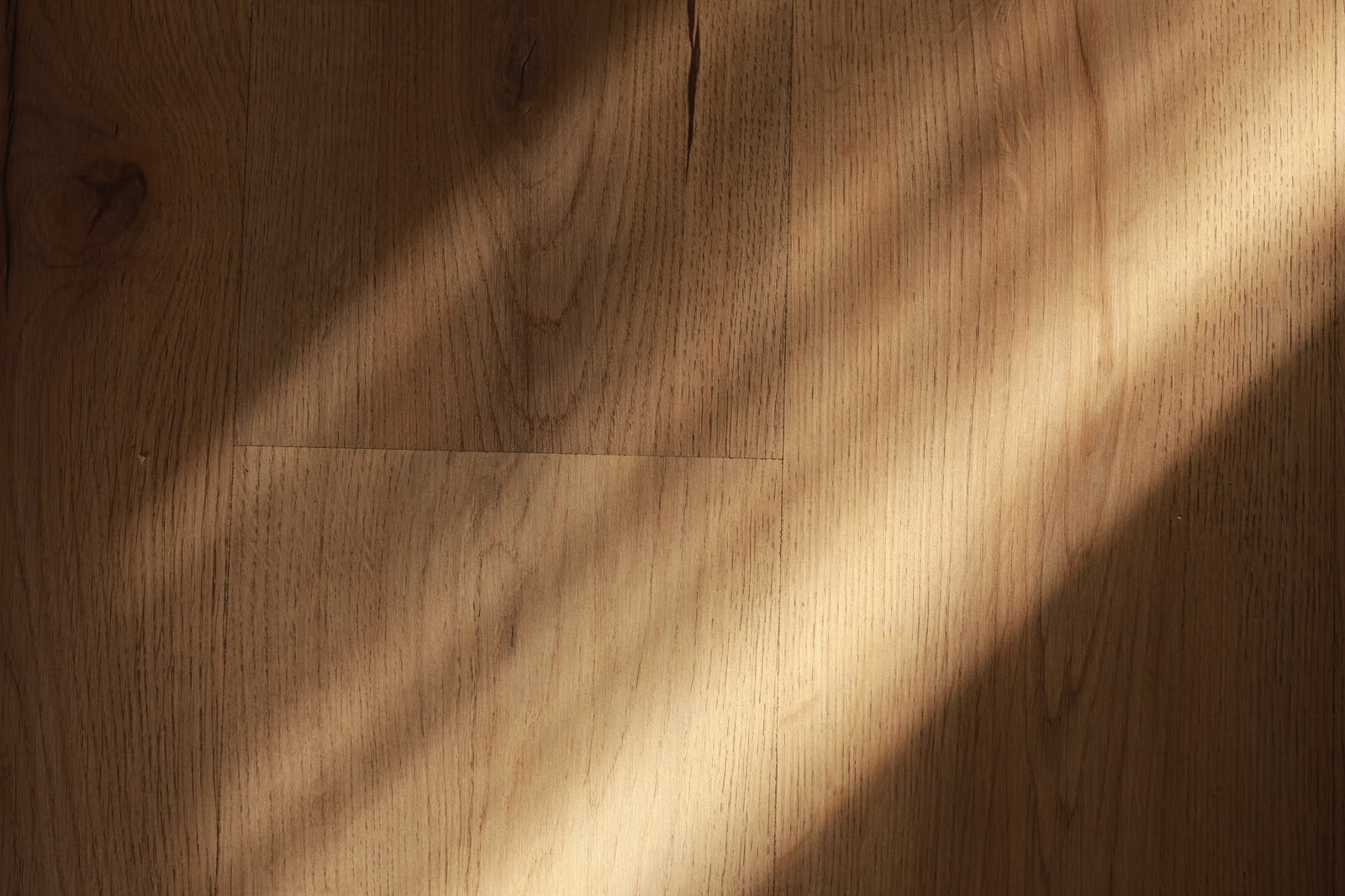 Sunlight casting diagonal shadows on wooden floorboards with visible grain and knots.