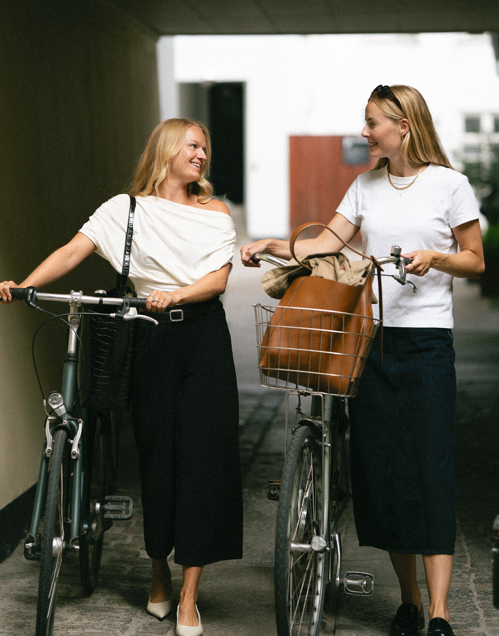 Julie Torp Rehn og Anna Labuhn Olesen trækker deres cykler gennem en port