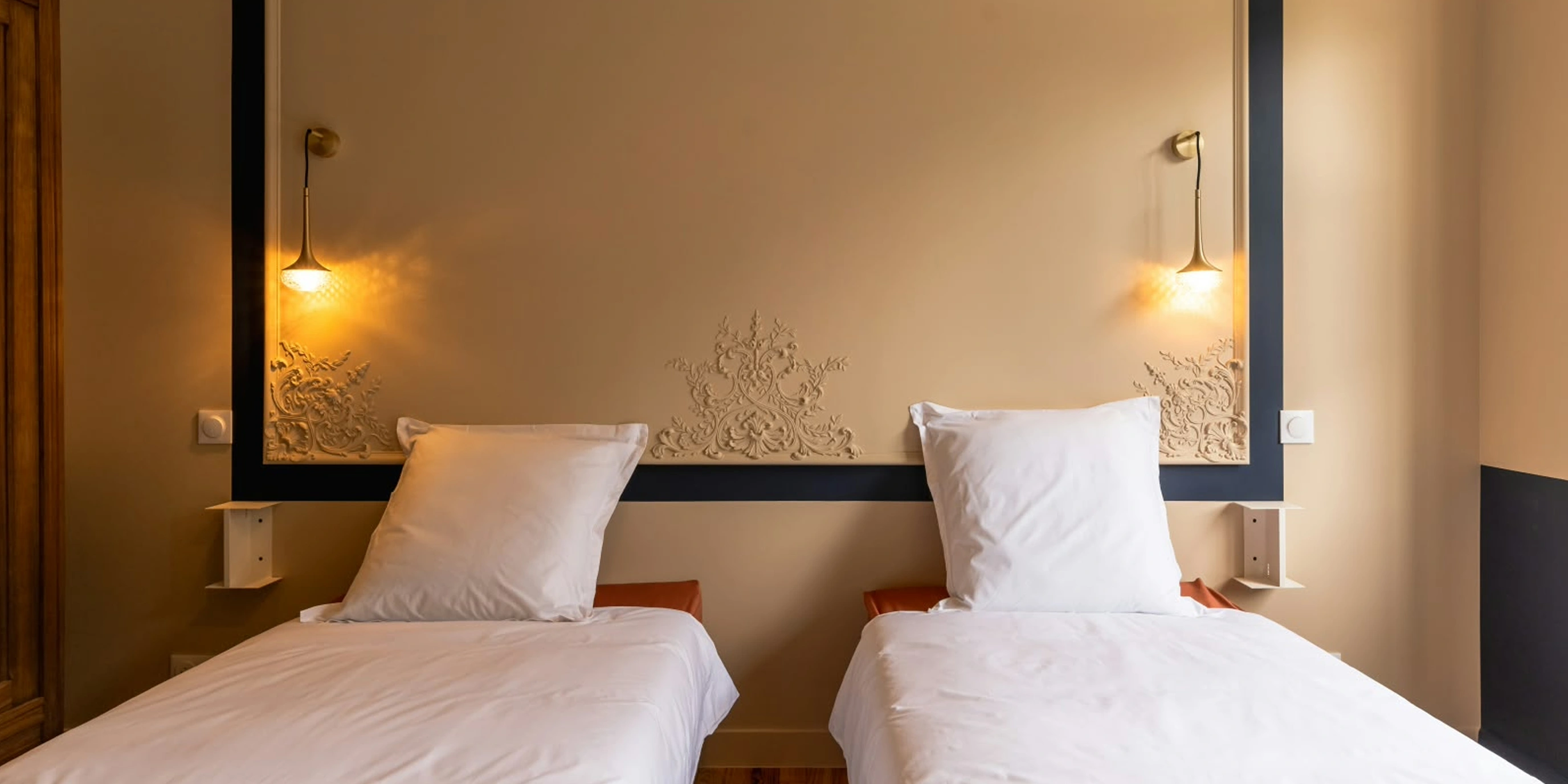 Chambre à deux lits avec tête de lit en staff et encadrement bleu marine