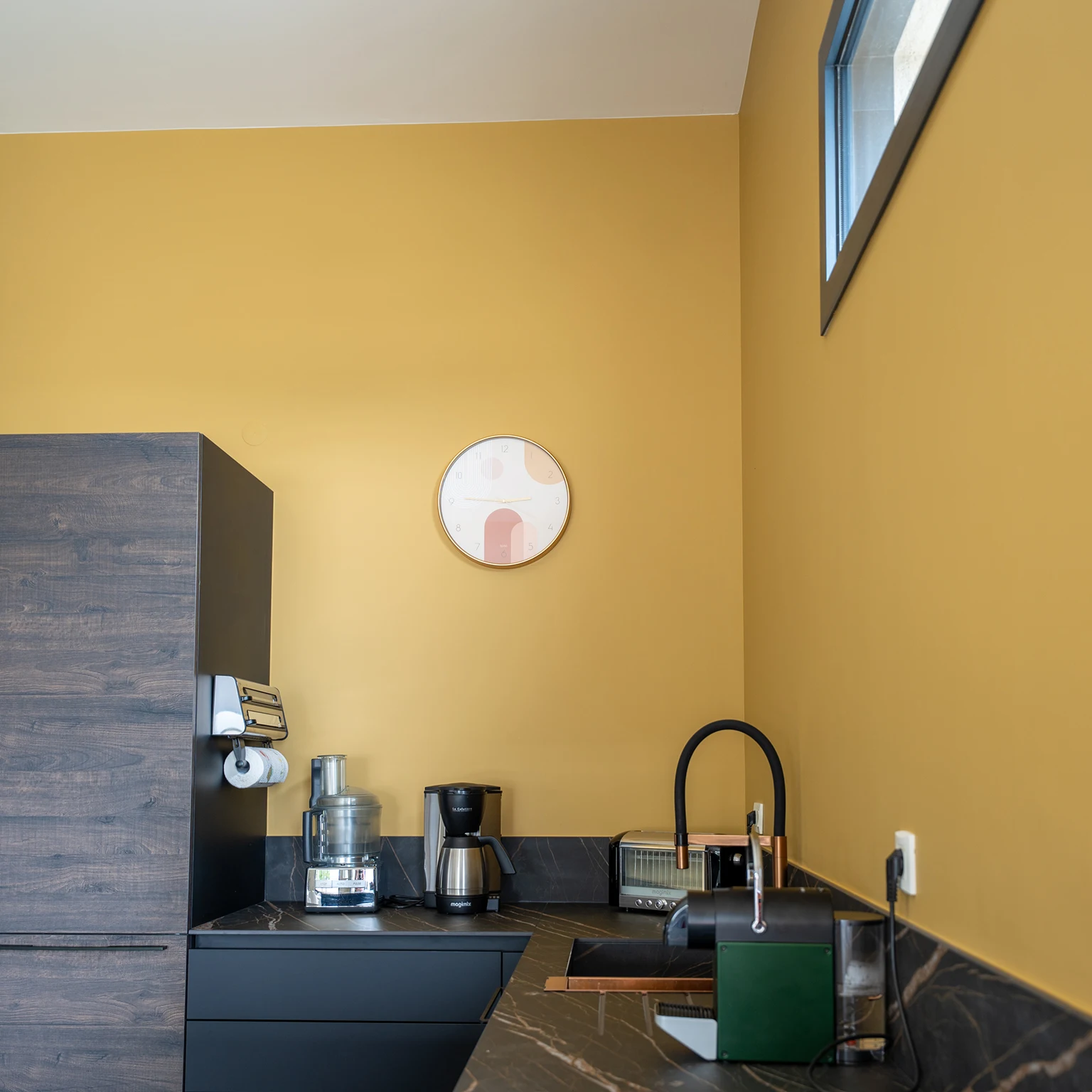 Cuisine avec mur jaune moutarde et plan de travail noir