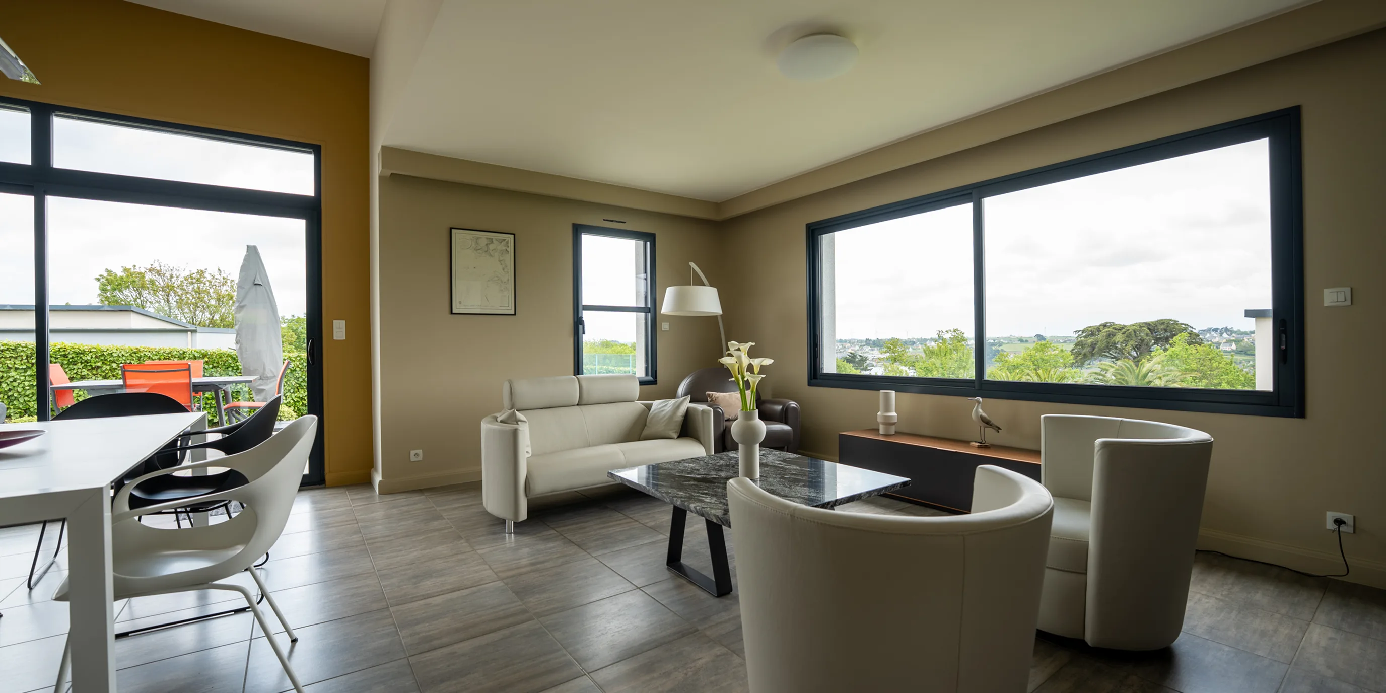 Salon aux murs kaki ouvert sur de grandes baies vitrées