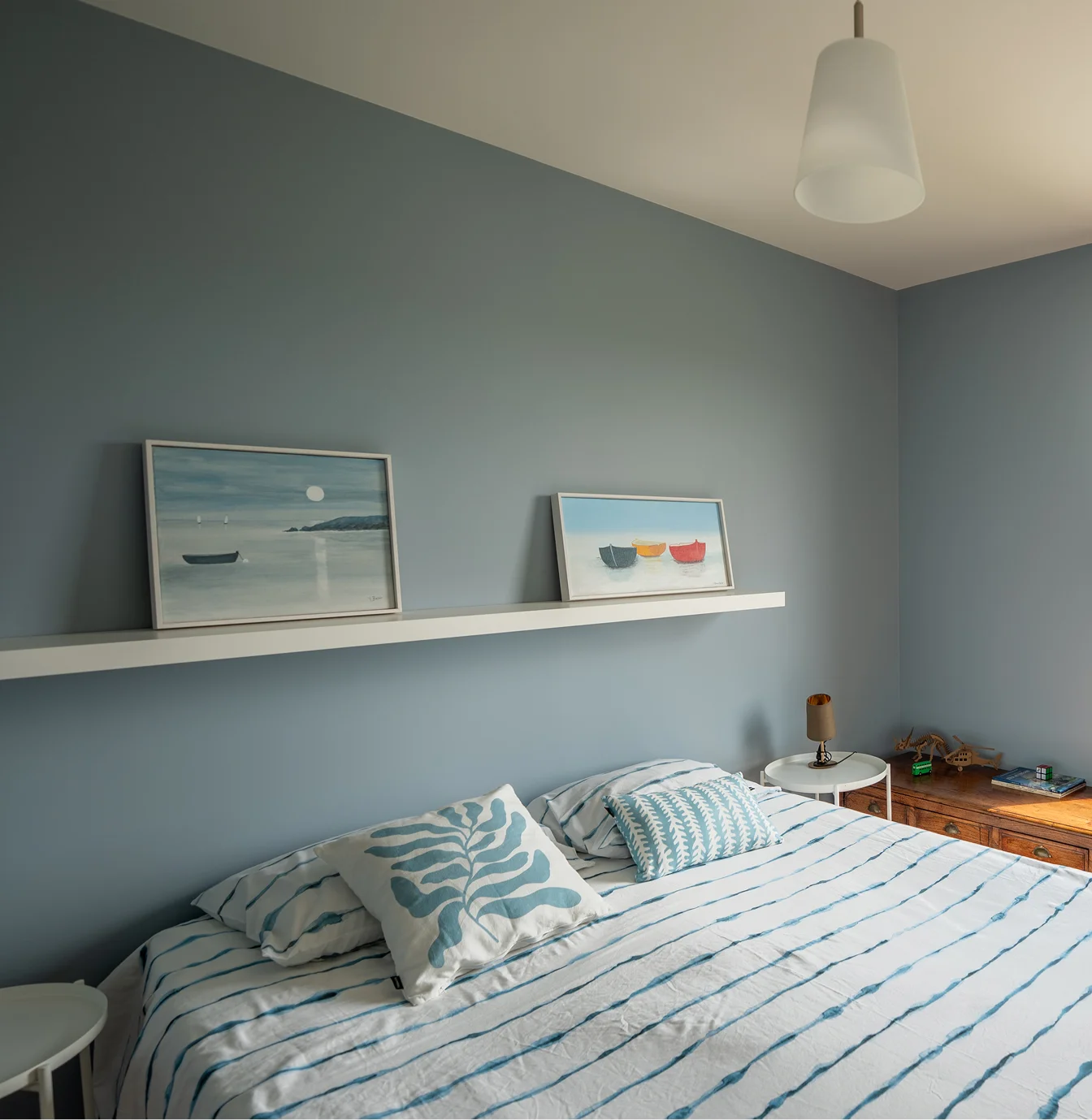 Chambre aux murs bleu gris avec étagère murale