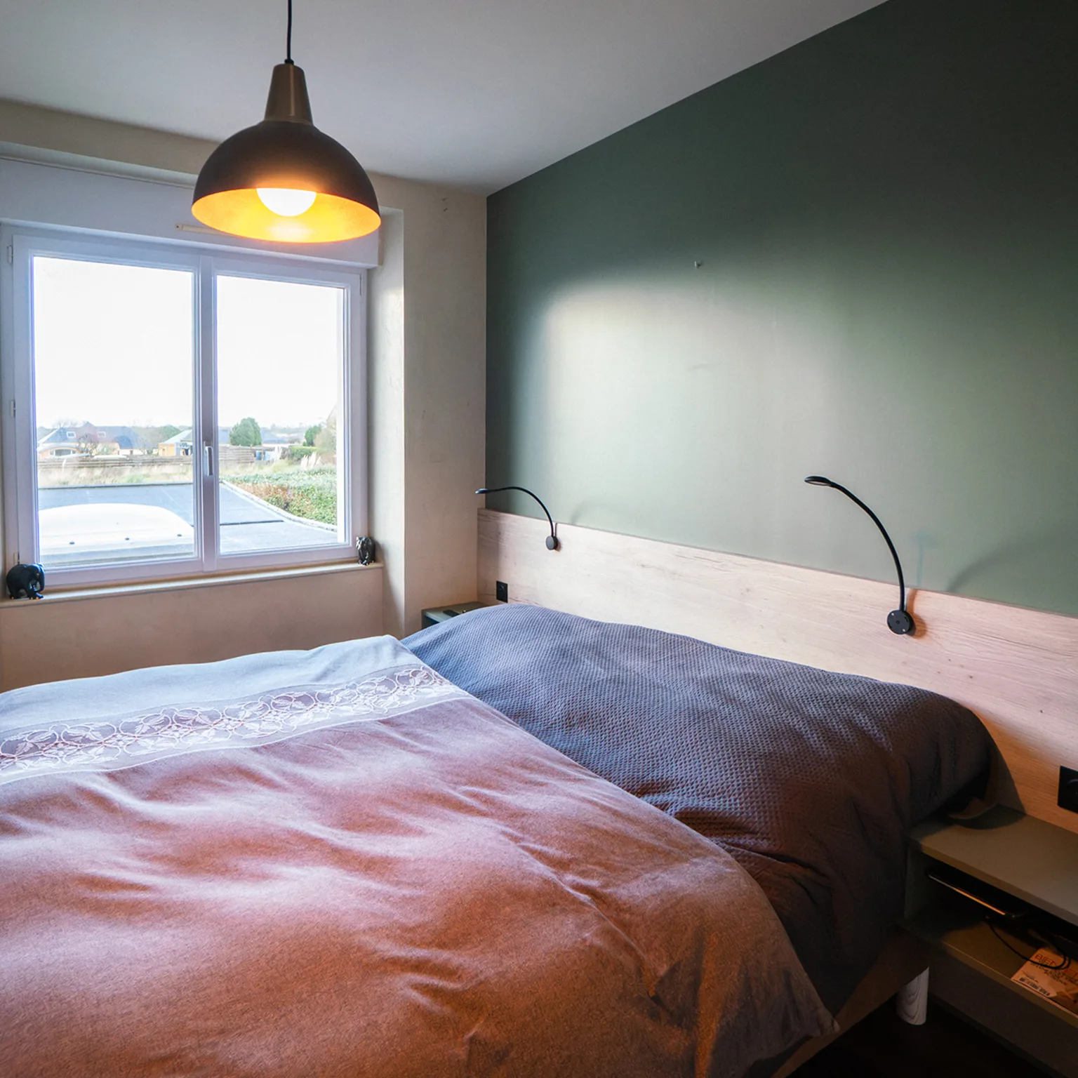Chambre avec mur vert sapin et tête de lit en bois