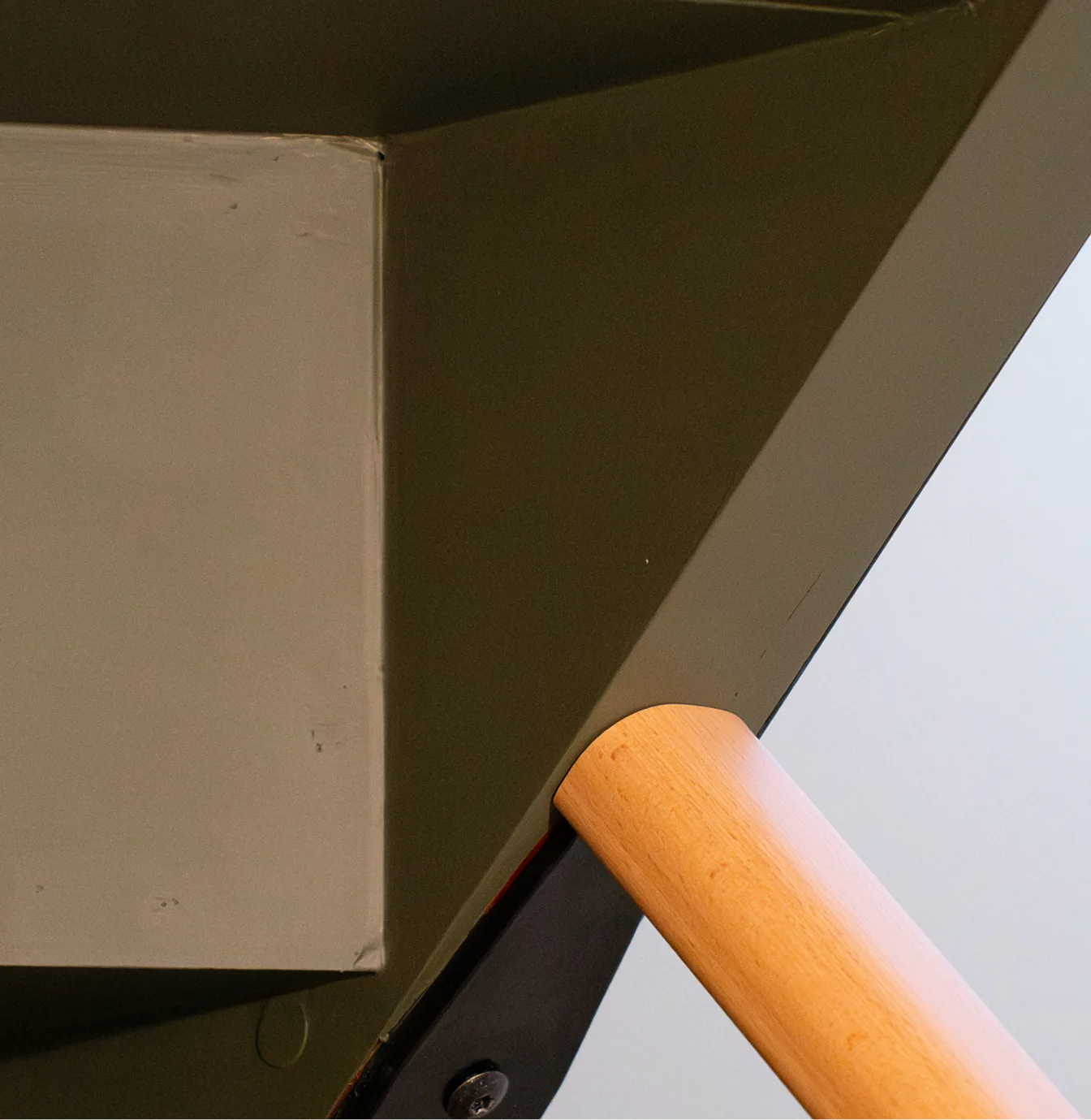 Détail de la main courante en bois sur mur vert foncé