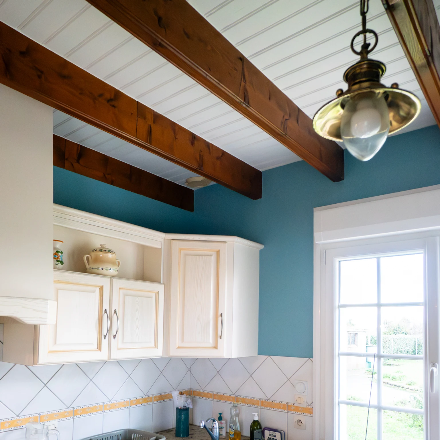 Cuisine avec mur bleu canard et poutres apparentes