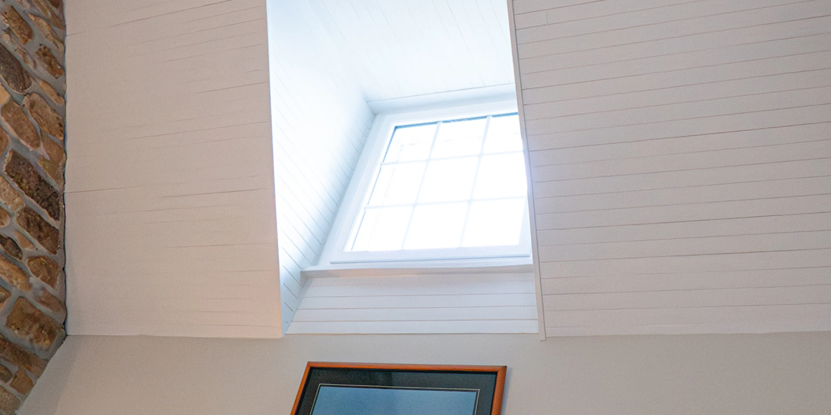 Plafond lambrissé blanc et fenêtre de toit dans la mezzanine