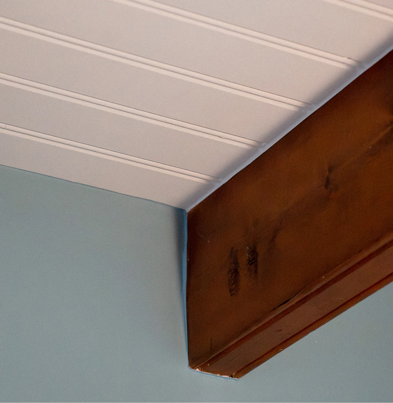 Poutre en bois apparente sur mur bleu et plafond blanc