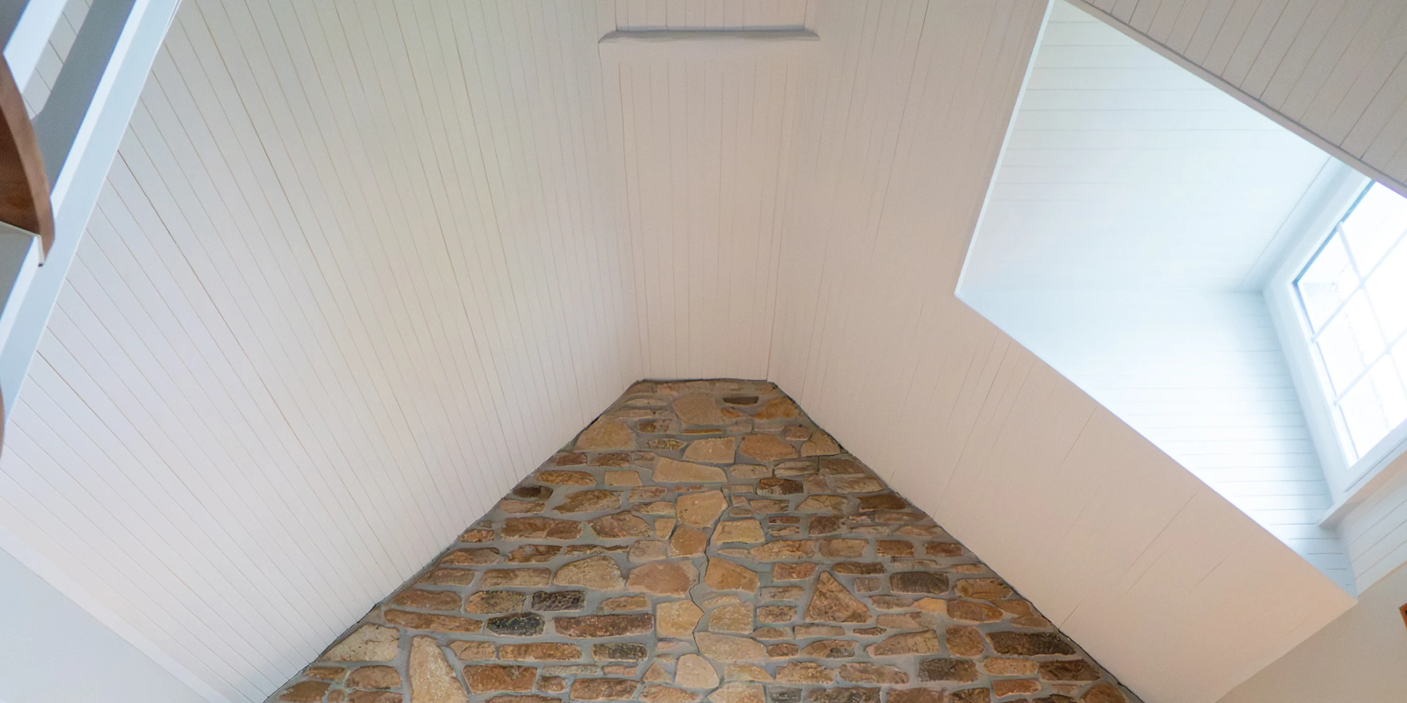 Mezzanine sous combles avec lambris blanc et mur en pierre