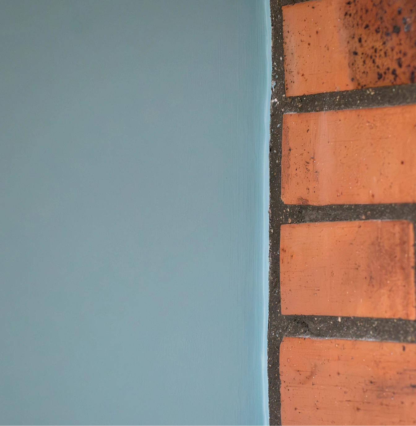 Raccord net entre mur bleu et briques apparentes