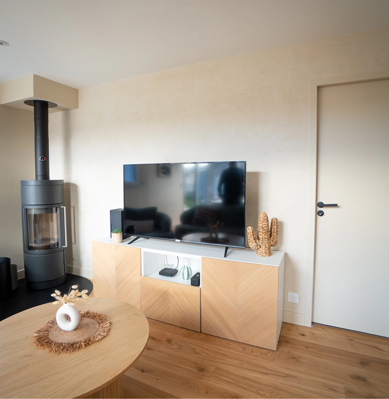 Salon avec poêle et mur en enduit décoratif beige
