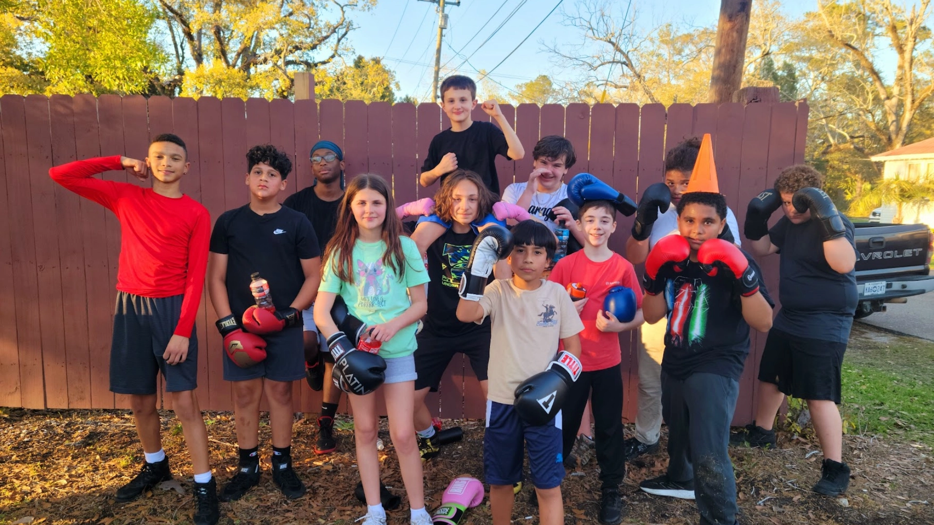 A group of children smiling and posing together, each wearing boxing gloves, ready for a fun photo opportunity.
