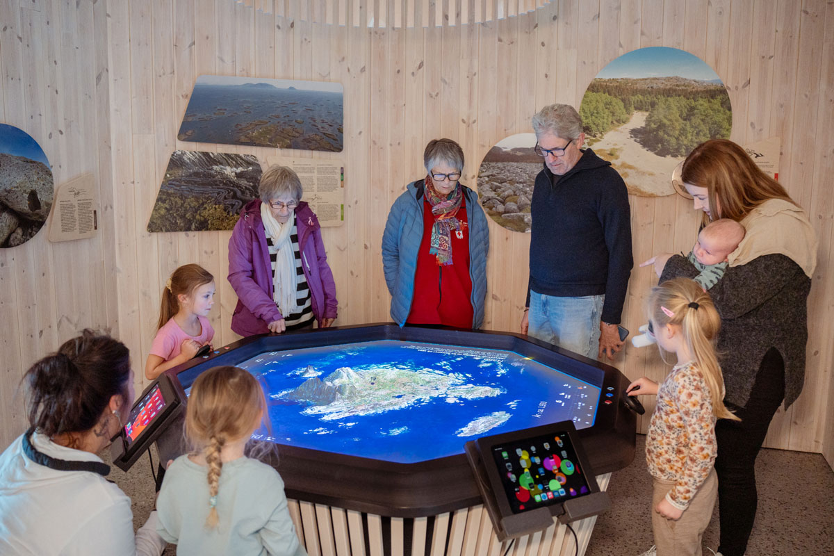 Besøkende utforsker et interaktivt kart i utstillingen på Vega Verdensarvsenter.