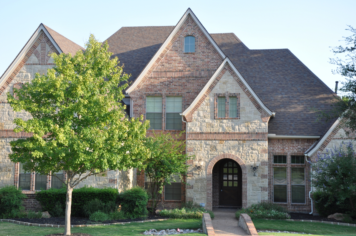 Front view of stone home with ivy-covered exterior and new shingle roof in Southlake TX