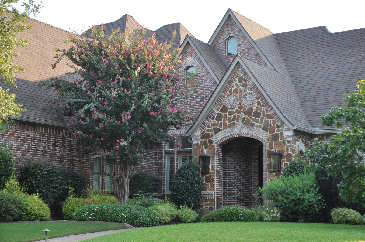 Corner view of luxury brick and stone home with new shingle roof in Southlake TX