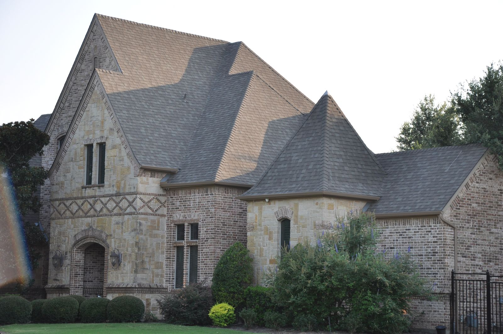 Front view of brick and stone home with landscaped yard and new shingle roof in Southlake TX