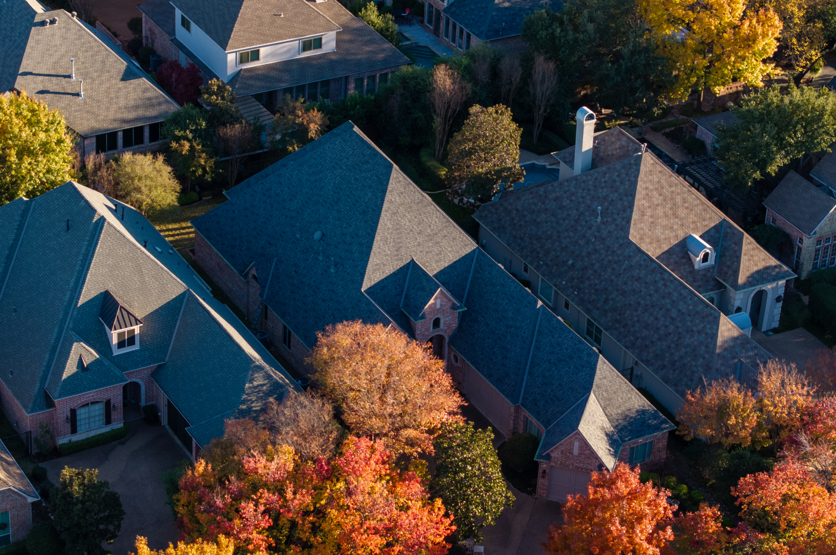Aerial view of large stone home with new dark shingle roof in Southlake TX
