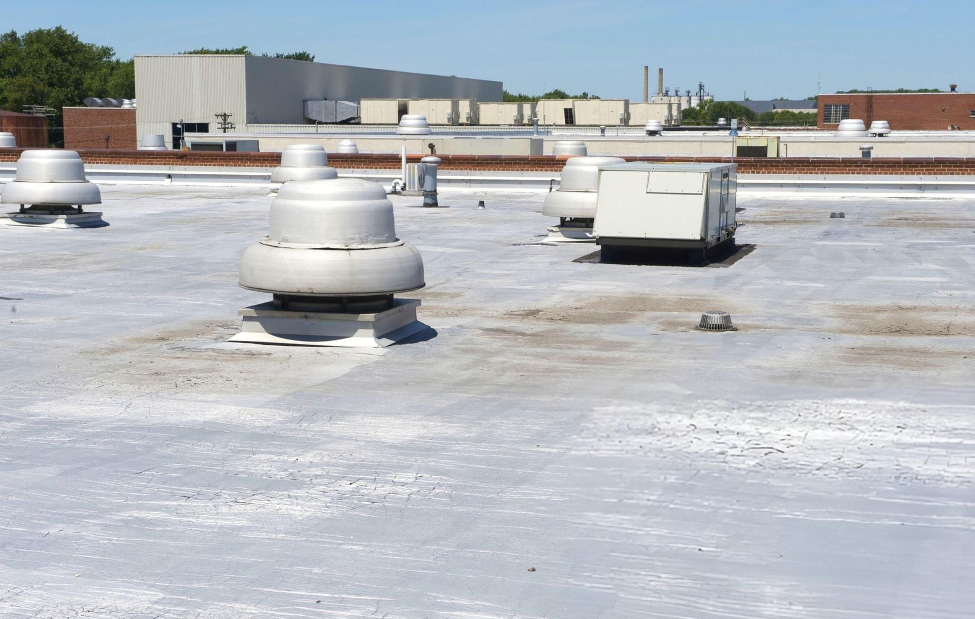 Flat commercial roof with ventilation systems, professionally maintained and protected by CLC Roofing for long-term performance.