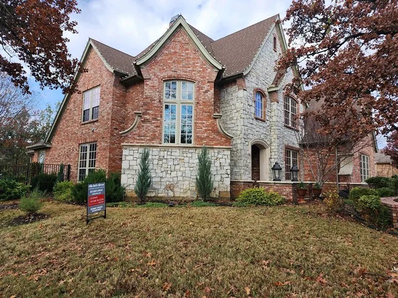 Two-story brick and stone home in Southlake, TX featuring a newly installed shingle roof by CLC Roofing.