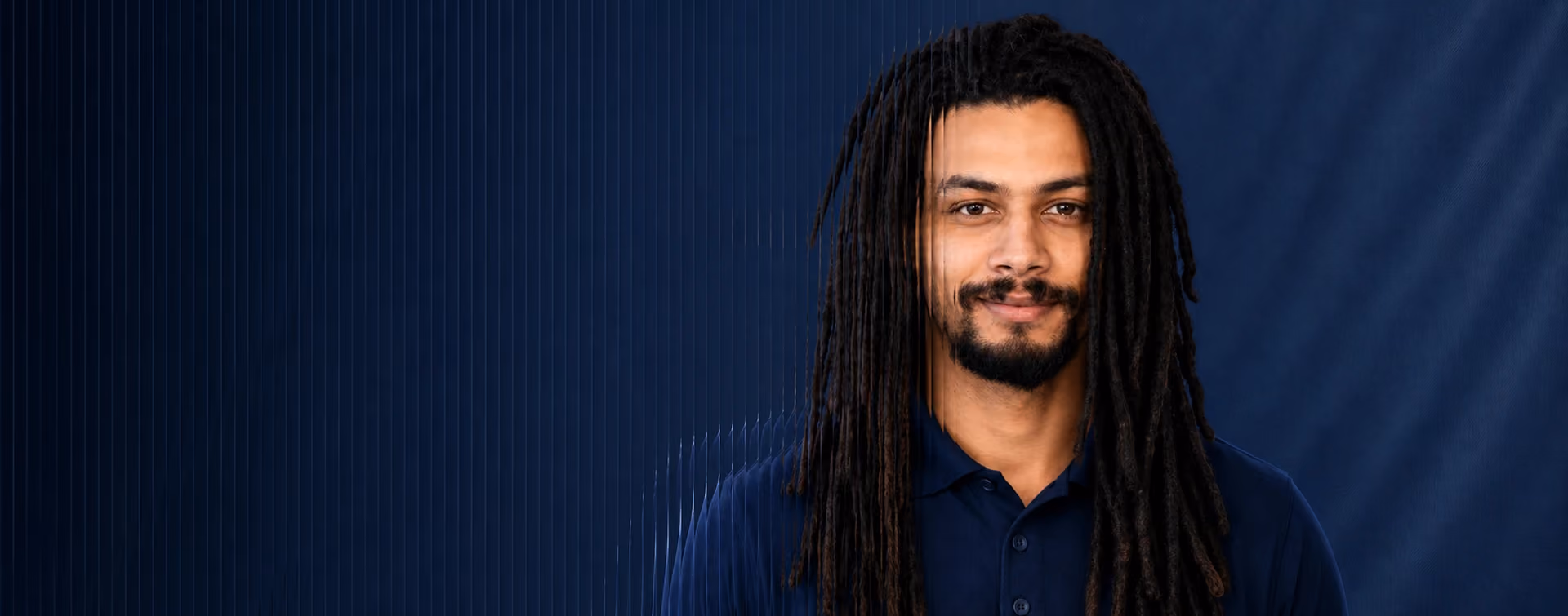 Team member portrait in a navy polo with a dark blue tech-inspired background and fluted glass distortion effect.