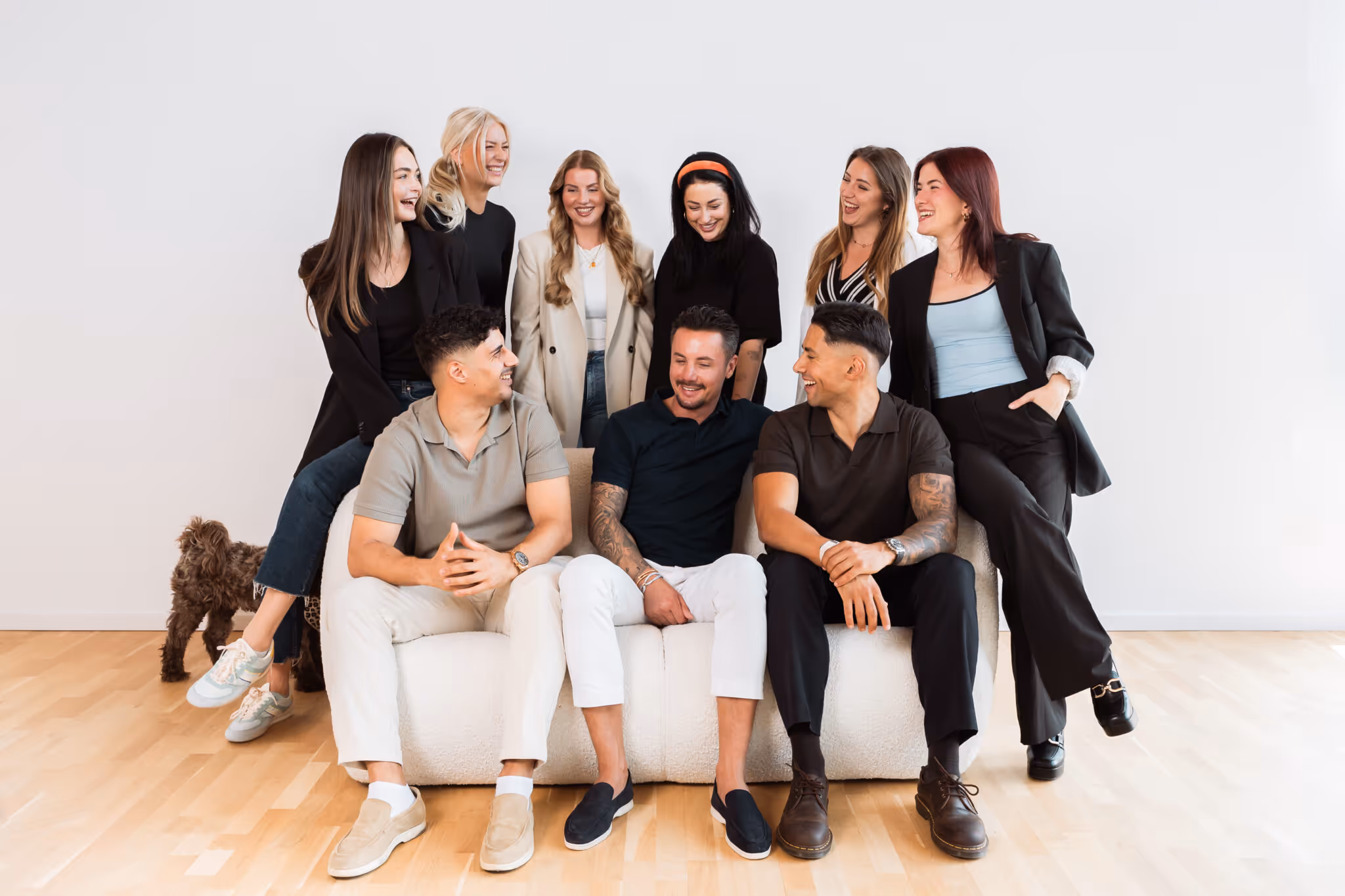 Das Team der StudioOne GmbH sitzt zusammen auf dem Sofa und alle schauen glücklich.