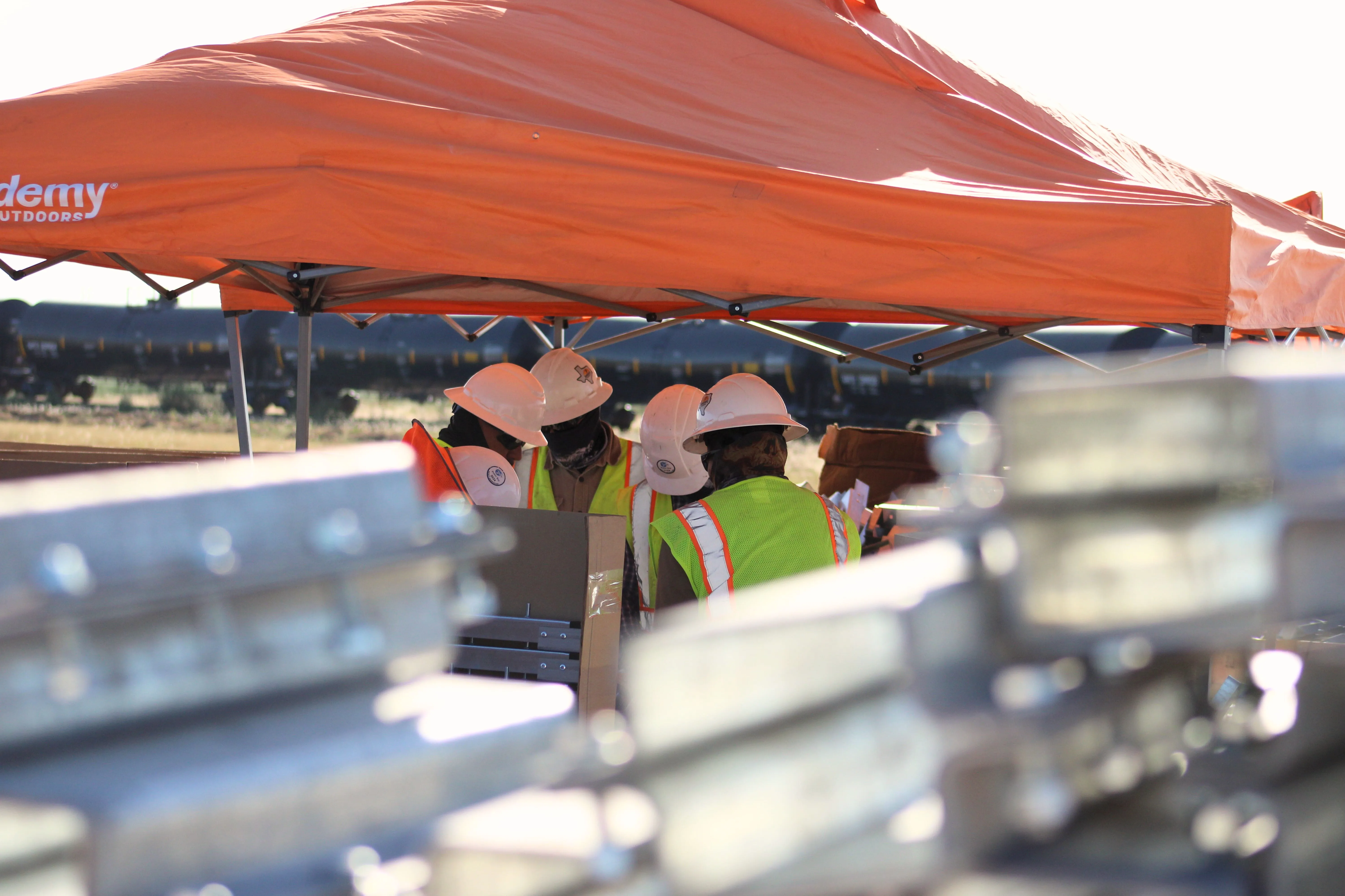 Crew members gathered under an orange tent with steel racking components in the foreground at the Diamond solar project