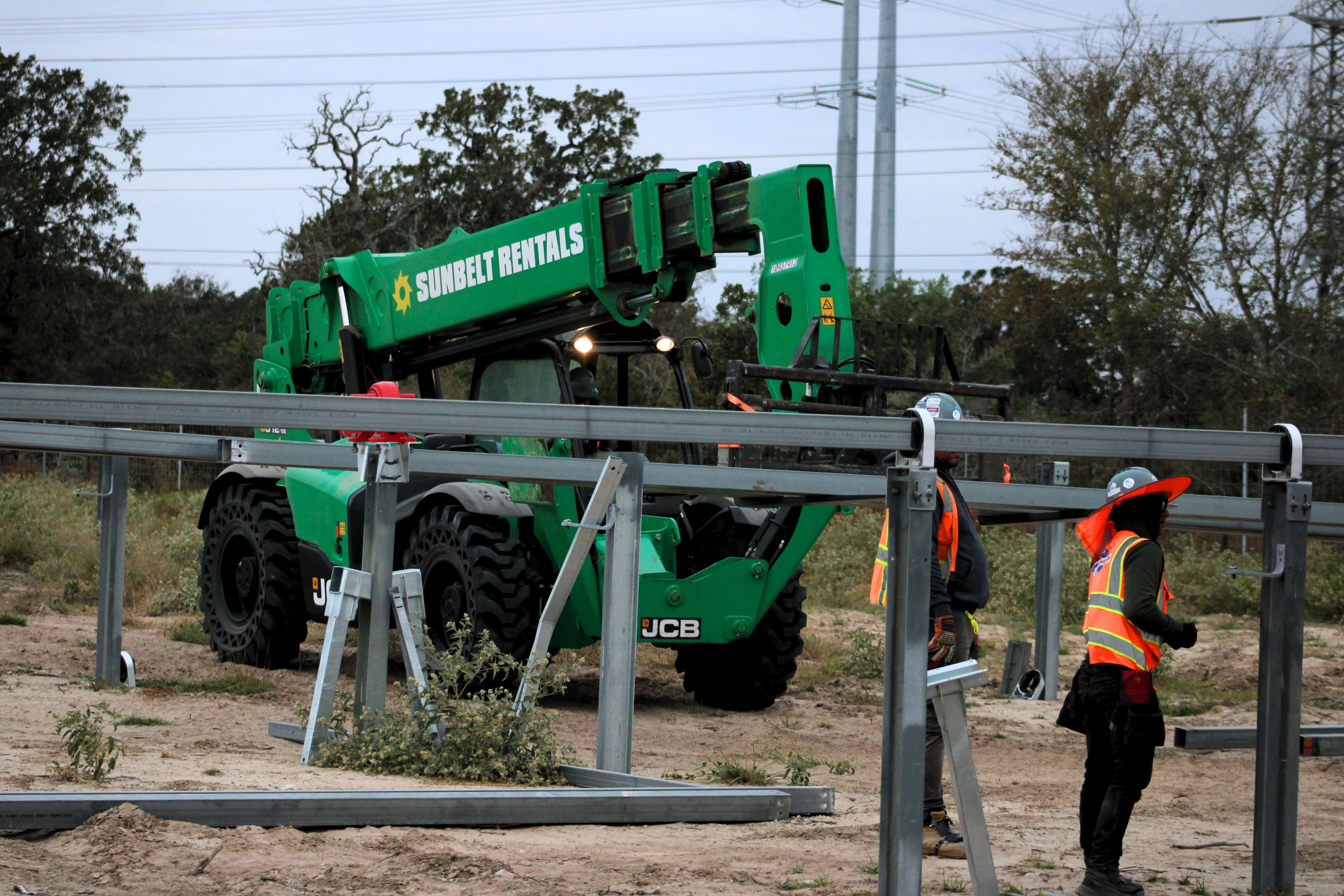 Telehandler and crew members working around steel racking at the Grimes solar site in Iola, Texas