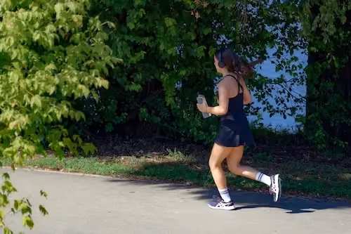 Girl running in Madrid on a sunny day,with trees and a lake in the background.