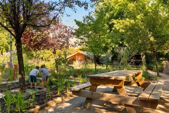 Children exploring a garden beside picnic tables at Cabaña del Retiro in Madrid