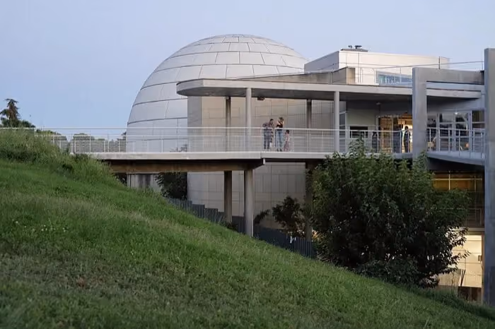 Exterior of Madrid Planetarium with its white dome and surrounding green hill