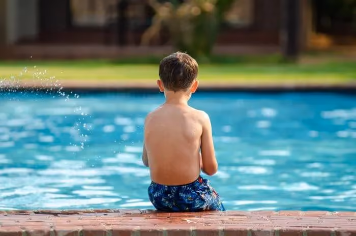 Child sitting at the edge of a swimming pool