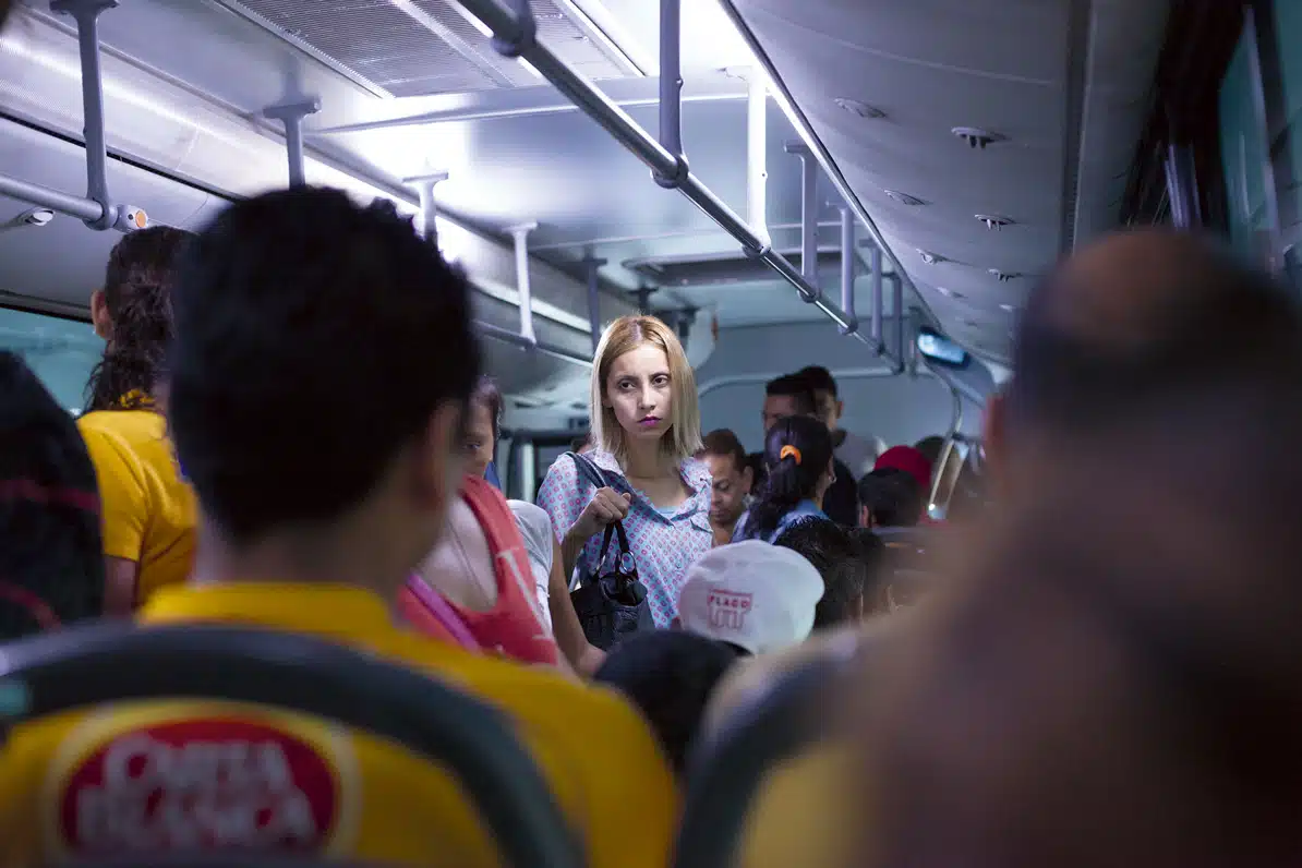 Photo from Alejandro Cartagena's exhibition, depicting a woman on a bus full of people.