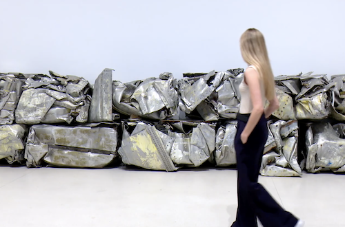 Person walking past Fernando Sánchez Castillo's compressed metal installation.