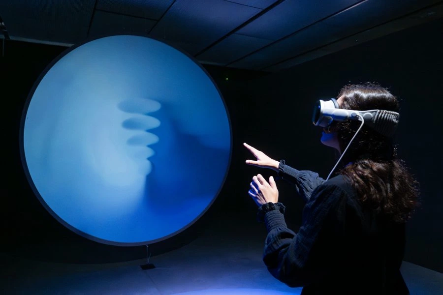 Visitor wearing a VR headset interacts with a glowing blue orb installation.