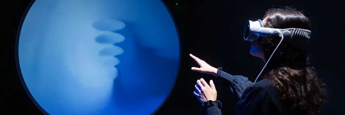 Visitor wearing a VR headset interacts with a glowing blue orb installation.