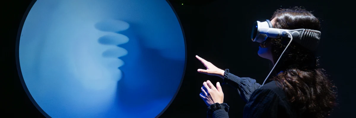 Visitor wearing a VR headset interacts with a glowing blue orb installation.