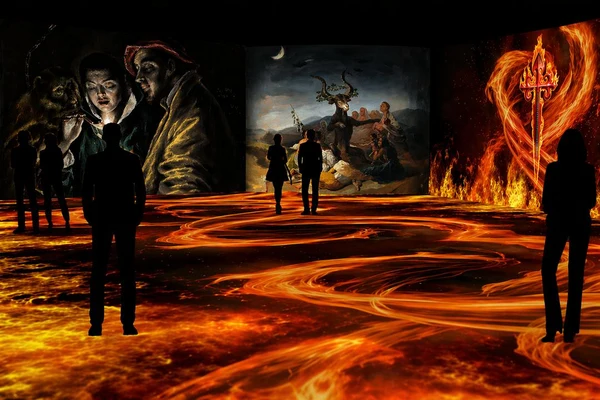 Visitors walk among fiery floor projections and screens showing El Greco, Goya and a fire-wreathed dagger at Nomad Museo Inmersivo.