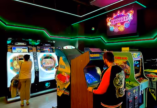 Guests enjoying classic arcade cabinets and rhythm games inside OXO Museo Madrid in Madrid