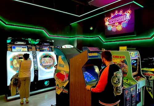 Guests enjoying classic arcade cabinets and rhythm games inside OXO Museo Madrid in Madrid
