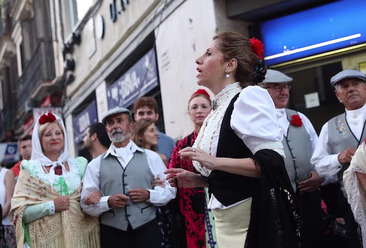 Personas con trajes tradicionales de chulapo y chulapa durante las fiestas de San Lorenzo en el barrio de Lavapiés, Madrid